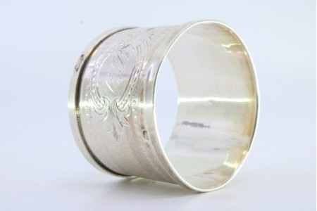 Argola de guardanapo em prata com centro escovado e frisos perlados envolvendo cartela para monograma.